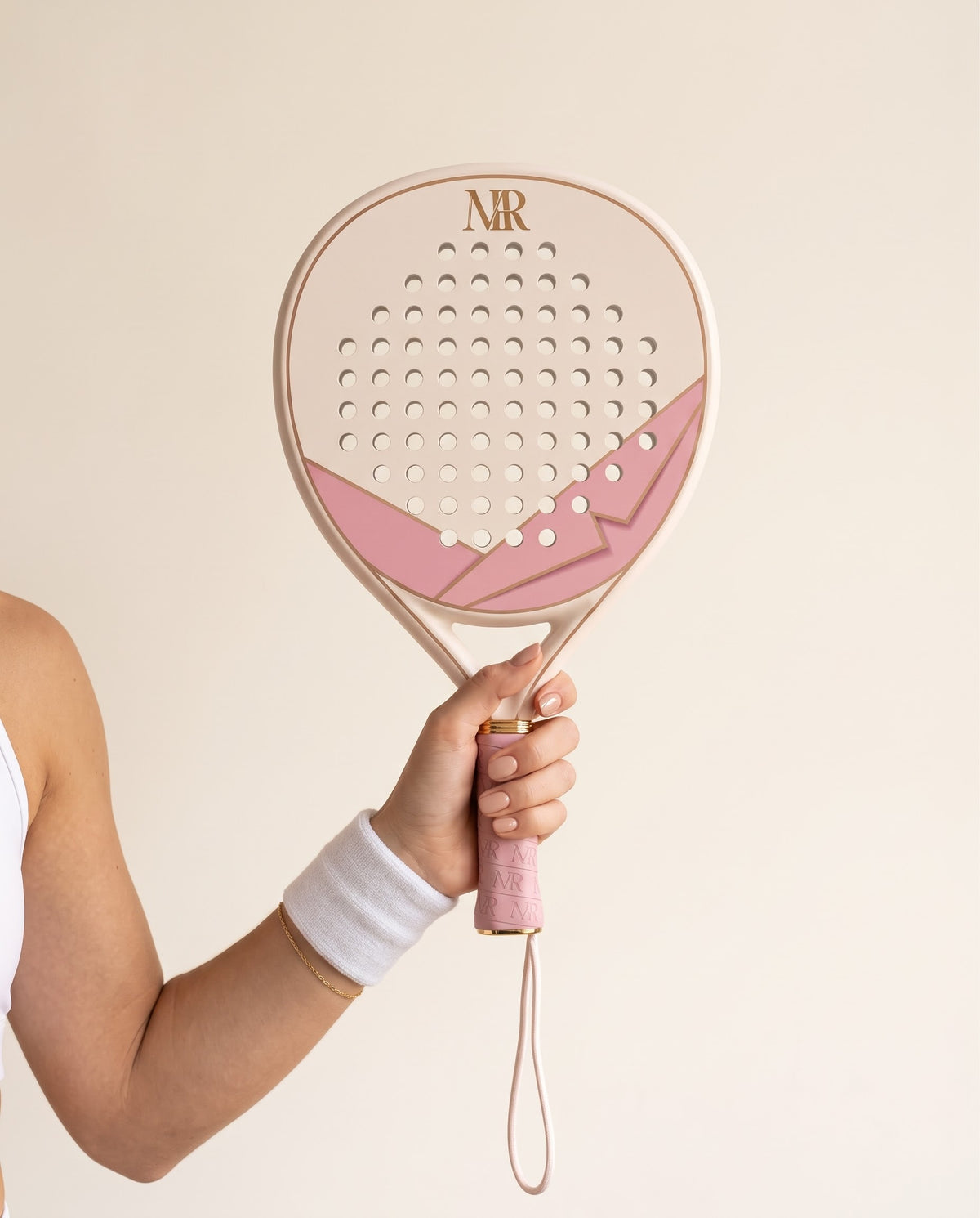Main manucurée tenant La Signature Crème, grip rose monogramme MR